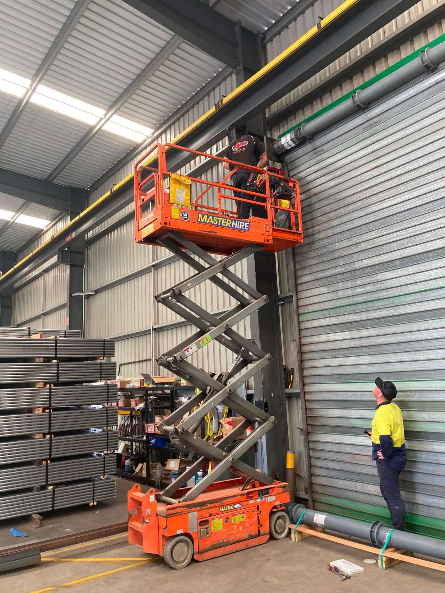 Limitless technician servicing a large industrial roller shutter from a scissor lift in a Toowoomba warehouse